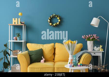 Interno del soggiorno decorato per Pasqua con divano e tulipani in vasi Foto Stock