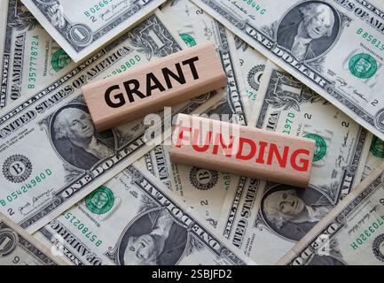 Simbolo di finanziamento della sovvenzione. Blocchi di legno con parole Grant funding. Bellissimo sfondo di dollari. Business e Grant funding. Copia spazio. Foto Stock