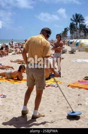 Uomo che usa il metal detector sulla spiaggia, Fort Lauderdale, 1974. Fotografia di Bernard Gotfryd. Foto Stock