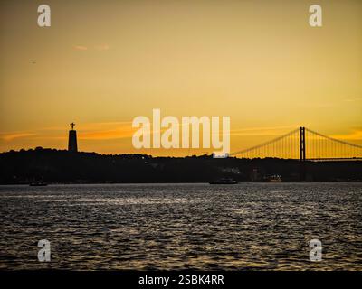 25 aprile Ponte e statua del Cristo Rei sul fiume Tago durante il tramonto. Ponte 25 de Abril simbolo di Lisbona durante un'ora d'oro. Foto Stock