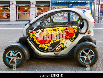 Porte in stile cartoni animati con paella su consegna al ristorante Renault Twizy veicolo elettrico plug-in microcar elettrico biposto parcheggiato a Madrid in Spagna Foto Stock