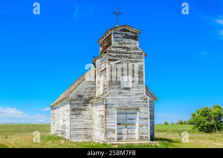 Chiesa bianca con una croce in cima. Sul tetto mancano le zampe. L'edificio è vecchio e abbandonato Foto Stock