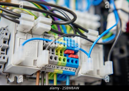 Fili colorati e componenti collegati alla morsettiera nella scatola di distribuzione. Scheda a circuiti elettrici con cablaggio e collegamenti Foto Stock