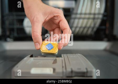 Primo piano della mano femminile che inserisce il detergente per lavastoviglie in un compartimento dispenser. Lavastoviglie efficiente e igienico Foto Stock