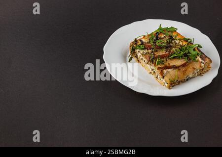 Goditi una fetta di pizza fatta in casa con cremoso formaggio fresco, pera dolce e rucola fresca, elegantemente presentata su un piatto delicato Foto Stock