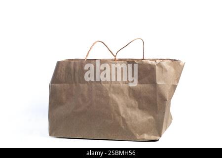 Un sacchetto di carta marrone progettato con robuste manici, ideale per il trasporto di generi alimentari, acquisti o imballaggi su sfondo bianco. Promuove la sostenibilità Foto Stock