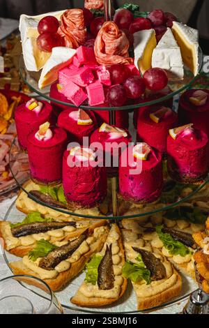Un incredibile assortimento di dessert è presentato su uno stand a più livelli, caratterizzato da vivaci torte rosa, uva fresca e prelibatezze salate uniche Foto Stock