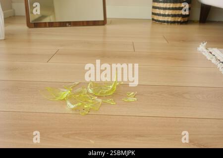 Vetri rotti sparsi su pavimento in legno Foto Stock