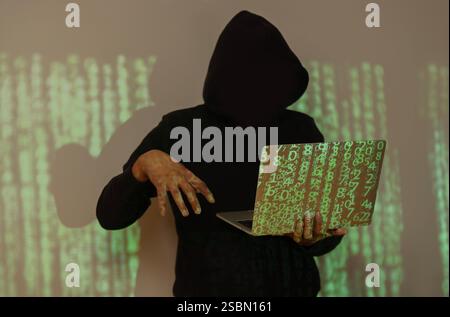 Colpo di hacker che usa un computer portatile. Molte cifre sullo schermo del computer. Prestare attenzione agli attacchi degli hacker. Foto Stock