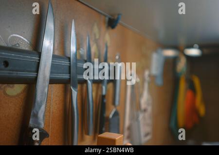 Vista ravvicinata dei coltelli da cucina fissati alla piastra magnetica. Foto Stock