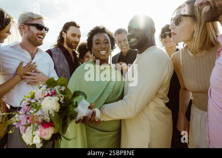 Ritratto di una coppia felice di sposi in mezzo a ospiti felici alla cerimonia di nozze Foto Stock
