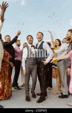 Felice coppia gay che si diverte con gli ospiti durante la cerimonia di nozze sul tetto Foto Stock