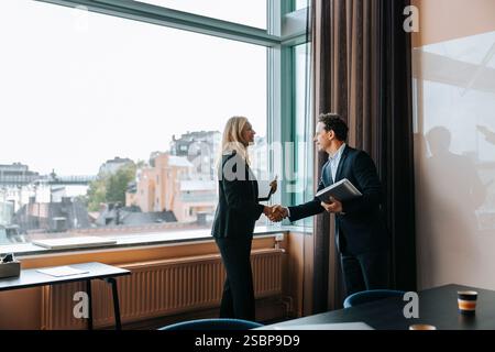 Professionisti di affari uomini e donne che si fanno strette di mano dopo una riunione in ufficio Foto Stock