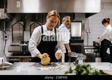 Una giovane chef che impastava l'impasto sul bancone della cucina del ristorante Foto Stock