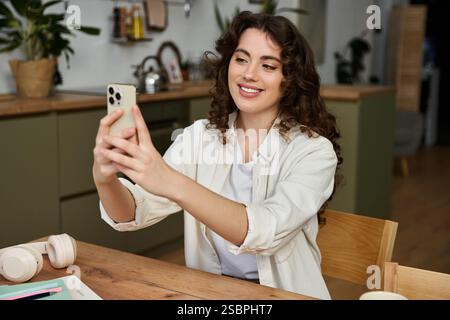 Una giovane donna si diverte a stare a casa, sorridendo e scattando un selfie. Foto Stock