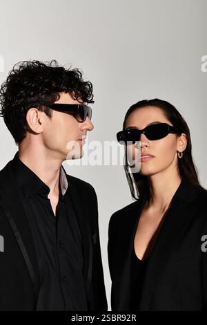 Due persone alla moda si mettono con fiducia in un abbigliamento alla moda, trasudando un'atmosfera chic. Foto Stock