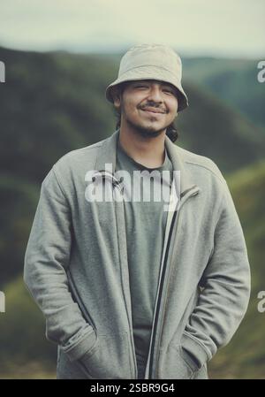 Ritratto di un giovane sorridente e attraente con cappello in un campo. Attraente giovane sorridente in cappello all'aperto Foto Stock