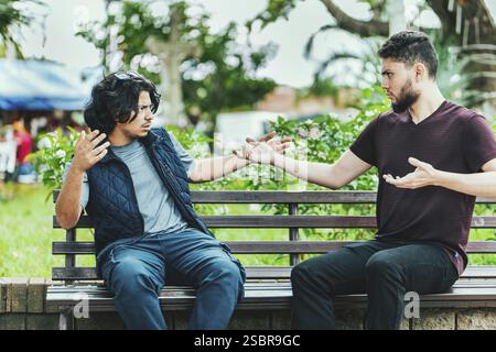 Due persone discutono su una panchina del parco. Due tizi che discutono seduti su una panchina Foto Stock