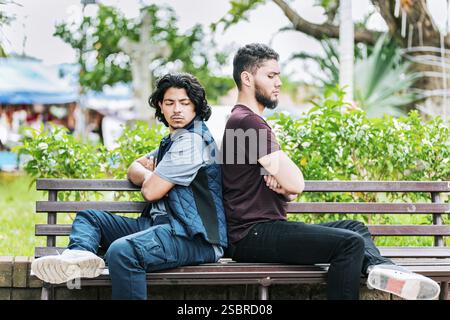 Due amici arrabbiati seduti su una panchina del parco. Due amici che discutono su una panchina del parco Foto Stock