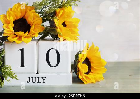 U. S. Energy Independence Day. Blocchi di calendario in legno bianco con la data del 10 luglio e bel bouquet di girasole con bokeh. Messa a fuoco selettiva. Foto Stock
