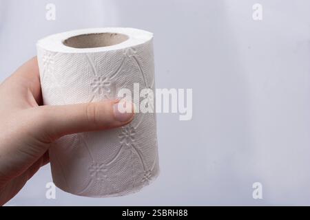 Una mano femminile prende in mano un rotolo di carta igienica bianca Foto Stock
