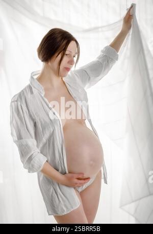 Donna incinta, madre incinta su sfondo bianco, primo piano della pancia incinta, attività durante la gravidanza Foto Stock