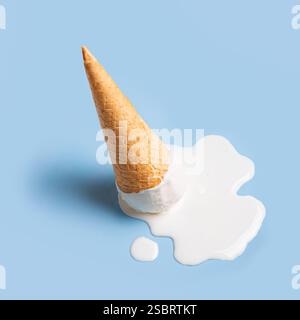 Gelato bianco che si scioglie e fuoriesce dal cono waffle su sfondo blu pastello. Concetto gastronomico estivo minimalista e alla moda. Cucchiaio di gelato alla vaniglia mel Foto Stock