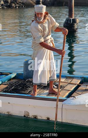 MUTTRAH, MASCATE, OMAN - 27 DICEMBRE 2024: Un pescatore locale sulla sua barca vicino al mercato del pesce Foto Stock