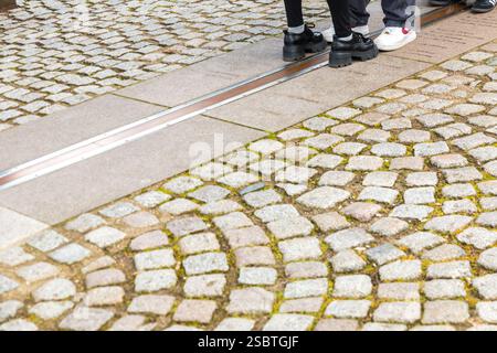 Vista ravvicinata dei turisti che si trovano tra il Greenwich prime Meridian, segnato dalla striscia di ottone sul terreno nel cortile del Royal... Foto Stock