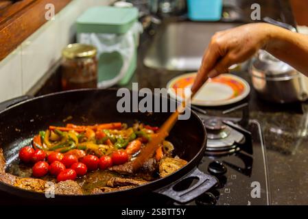 Bistecca con cipolle e pomodori rossi preparati in una cucina residenziale. Foto Stock