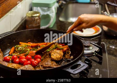 Bistecca con cipolle e pomodori rossi preparati in una cucina residenziale. Foto Stock