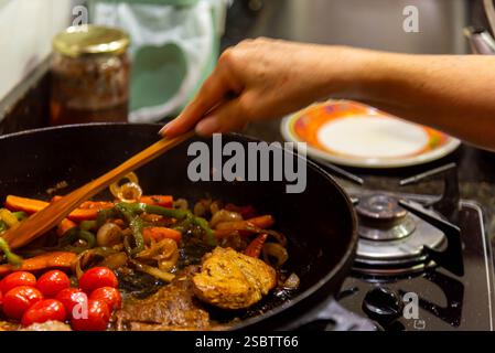 Bistecca con cipolle e pomodori rossi preparati in una cucina residenziale. Foto Stock