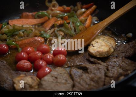 Bistecca con cipolle e pomodori rossi preparati in una cucina residenziale. Foto Stock