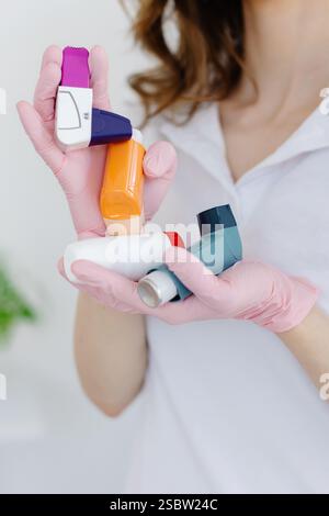 Medico donna che tiene e mostra inalatore per asma. Apparecchiature medicali portatili per attacchi di asma. Foto Stock
