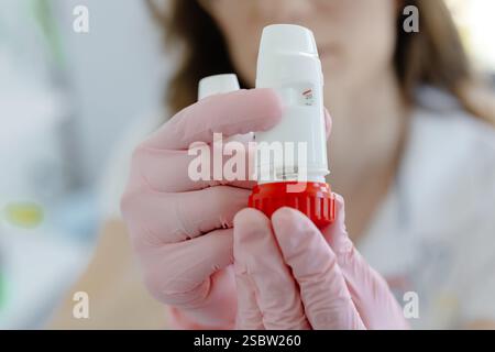Medico donna che tiene e mostra inalatore per asma. Apparecchiature medicali portatili per attacchi di asma. Foto Stock