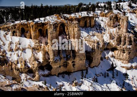 Una montagna con neve su di essa e qualche albero. La montagna è rocciosa e ha molte grotte Foto Stock