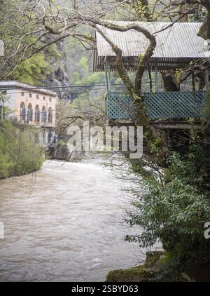 Casa sull'albero in legno che si affaccia su un fiume circondata da vegetazione lussureggiante e architettura rustica Foto Stock
