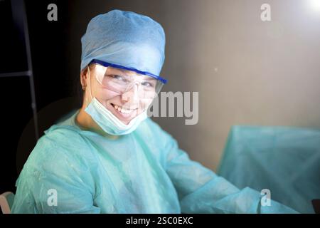 Un allegro operatore sanitario in abbigliamento blu sorridente calorosamente Foto Stock