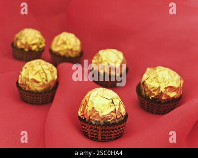 Confezione in Golden Candy Wrapper su sfondo Red Textile Foto Stock