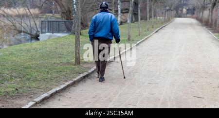 vecchio con bastone che cammina nel parco Foto Stock