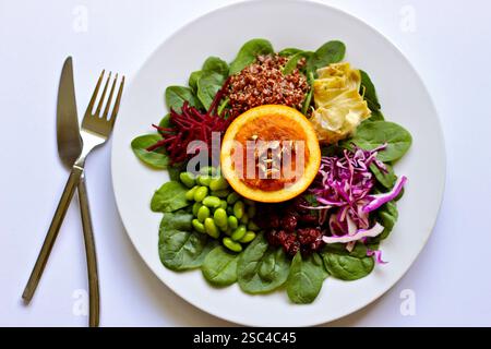 Insalata colorata composta con patate dolci all'arancia, spinaci, quinoa e verdure su sfondo bianco Foto Stock