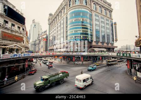 Una vivace scena di strada a Shanghai caratterizzata da traffico ed edifici commerciali con segnaletica prominente. Foto Stock