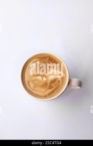Vista dall'alto di una tazza di caffe' latte fresco con belle opere d'arte su crema di latte. Studio minimalista realizzato su uno sfondo bianco brillante. Foto Stock