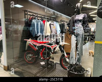 Kiev, Ucraina - 4 febbraio 2025: Moderno espositore al dettaglio con motocicletta e abbigliamento elegante. Foto Stock