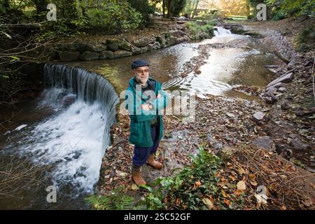 Stephen Ainsleigh Rice, accanto al fiume che passa davanti a casa sua. Attualmente sta costruendo un sistema idrico sul fiume che genererà 6 kW che riporterà nella National Grid. Foto di Mike Goldwater Foto Stock