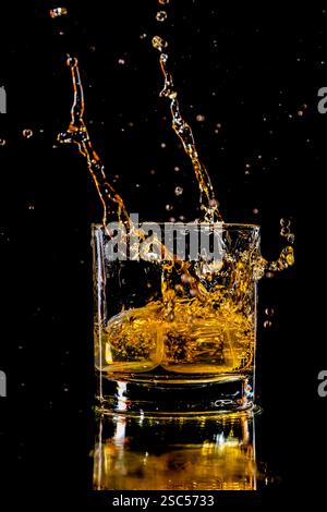 spruzzare il whisky in un bicchiere con due cubetti di ghiaccio Foto Stock