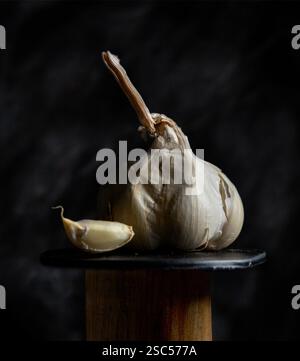 Uno spicchio d'aglio e uno spicchio d'aglio intero su una base di legno Foto Stock
