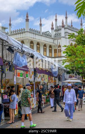 Turisti e gente del posto attratti dalle bancarelle alimentari di Ramadhan in Muscat Street a Singapore all'ombra della Moschea del Sultano, punto di riferimento religioso di Kampong Glam Foto Stock