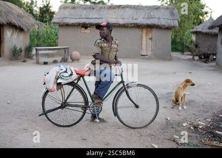 MAKEFU VILLAGE, IDODI DIVISION, TANZANIA OCCIDENTALE, maggio 2008: Un abitante del villaggio sulla strada di casa in bicicletta aspetta un amico. La bicicletta è la principale forma di trasporto per tutti i gusti in entrata e in uscita dal villaggio. Foto Stock