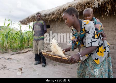 MAKEFU VILLAGE, IDODI DIVISION, TANZANIA, maggio 2008: Catherine Msigwa, 20 anni, porta il suo figlio di 6 mesi Pendo mentre inghiottisce il mais mentre suo marito Simon Oboaba, 25 anni, si trova accanto alla loro piccola casa. Foto Stock